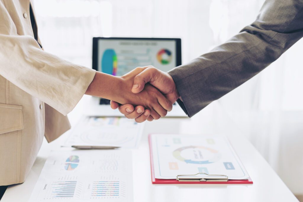 People shaking hands over paper after a meeting