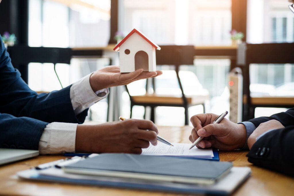 people having meeting with one holding mini house in hand