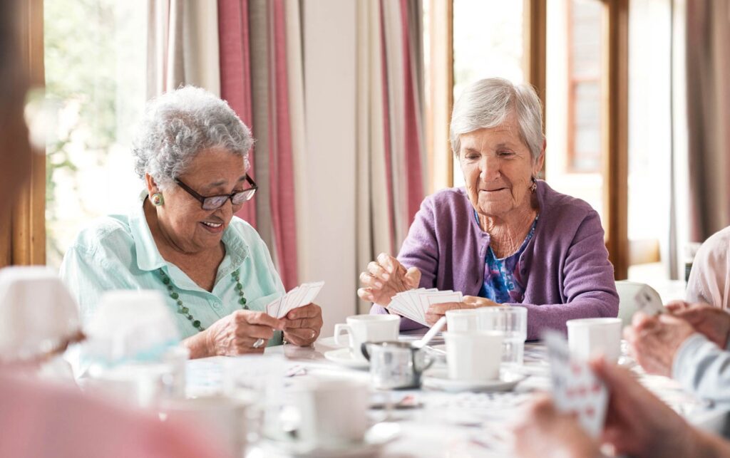 Two elderly women playing cards at a table