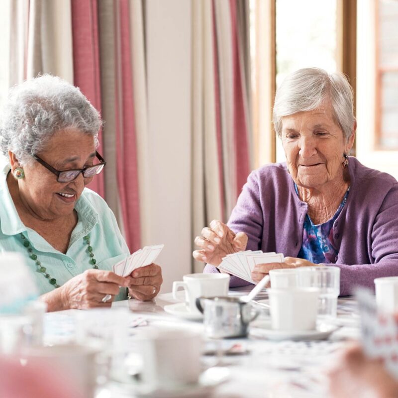 Two elderly women playing cards at a table