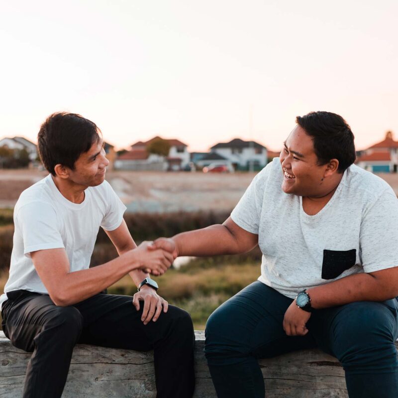 Two young Asian man come to an agreement at the park.