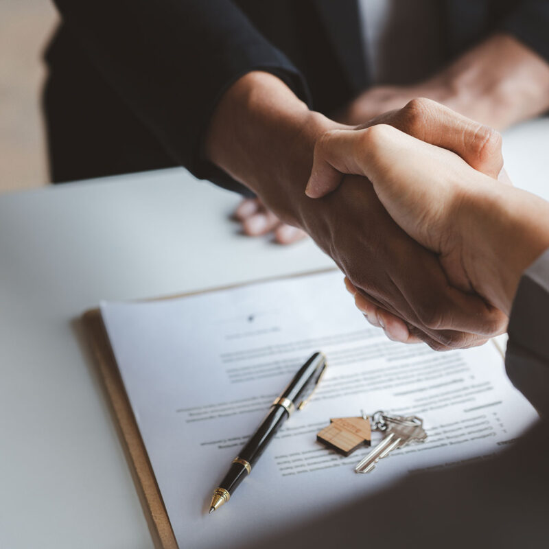close up of hands shaking over contract on table