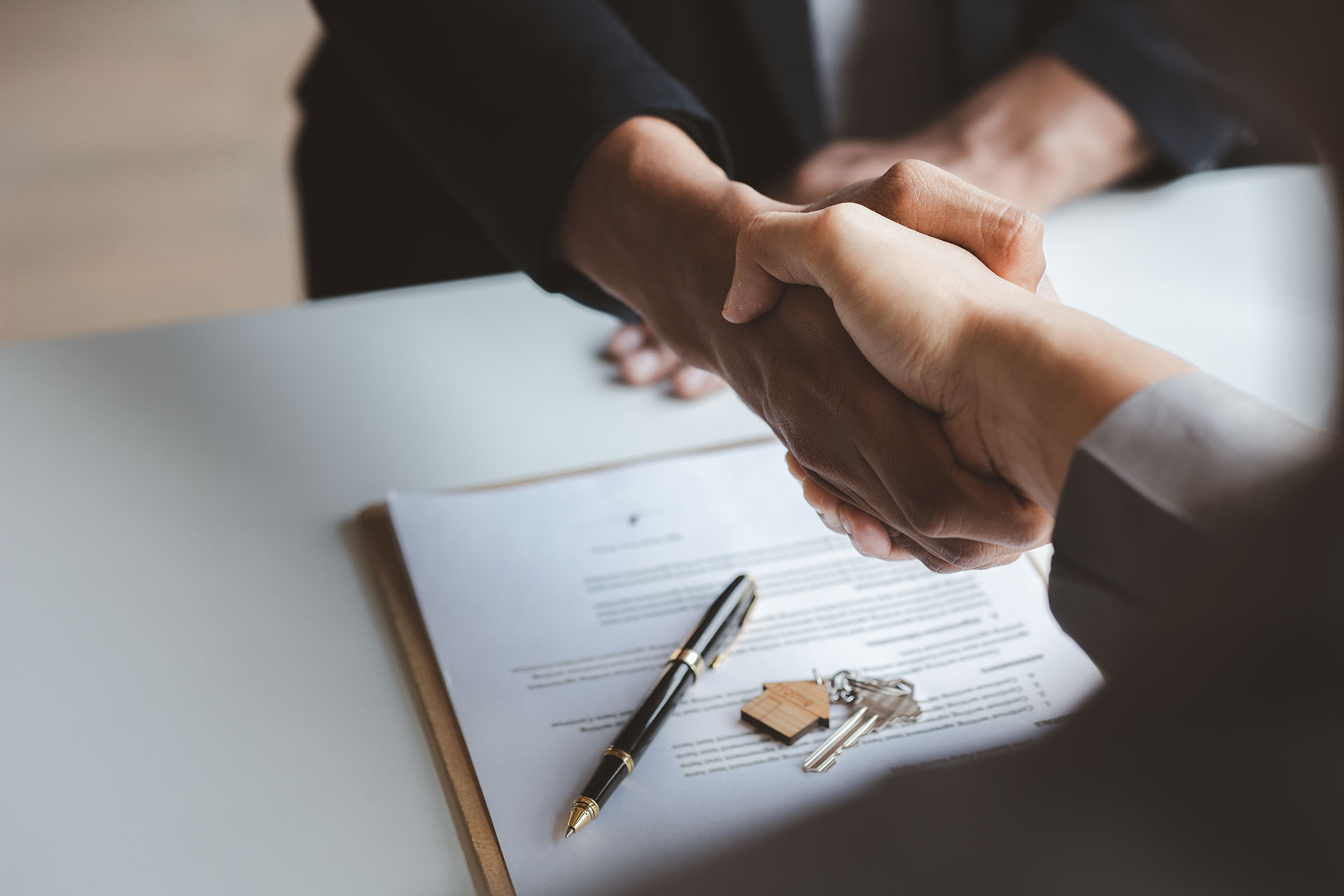 close up of hands shaking over contract on table