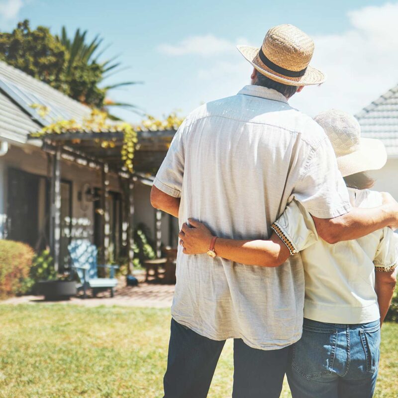 back view of couple hugging while looking at home